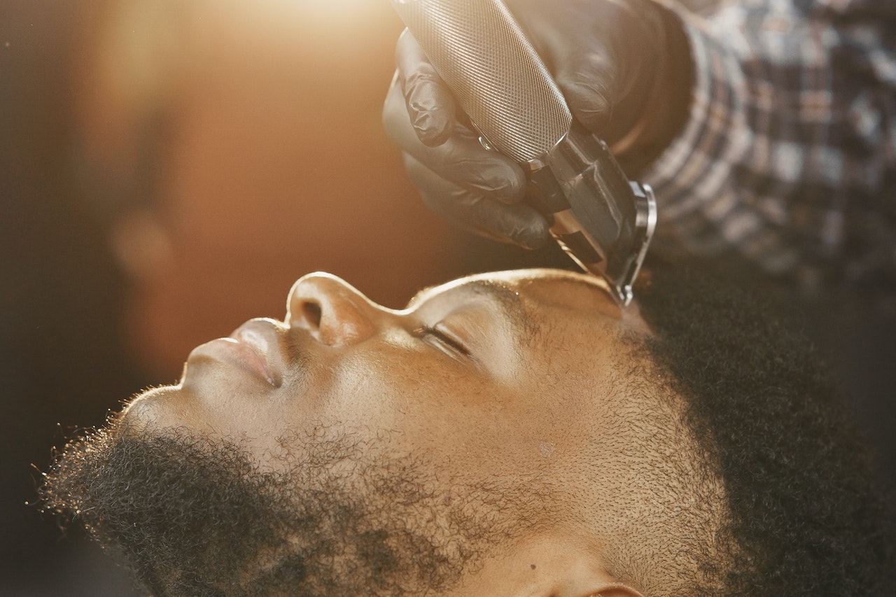 Client reclining in barber chair with a contented grin, illuminated by soft light.